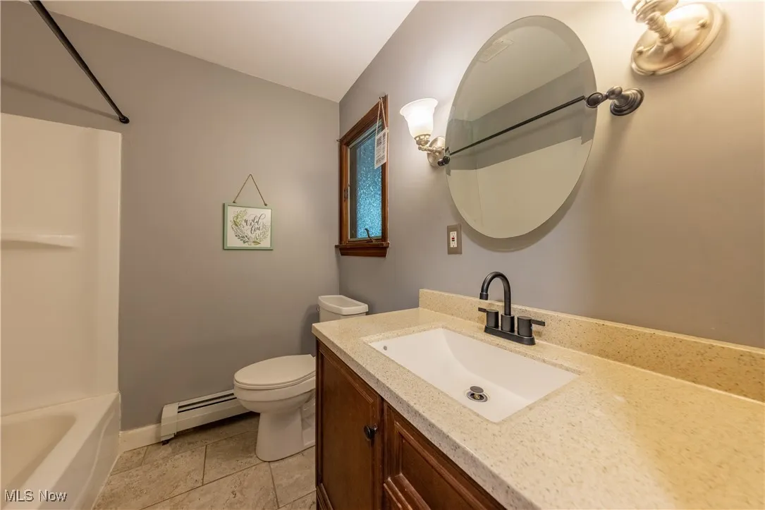 Full bathroom with single vanity and tub / shower combination located in the hallway on the first floor