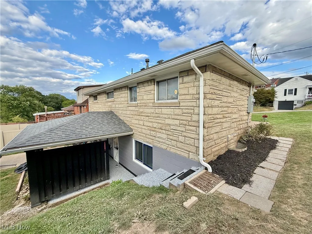 Rear view of house with stone siding and a lawn