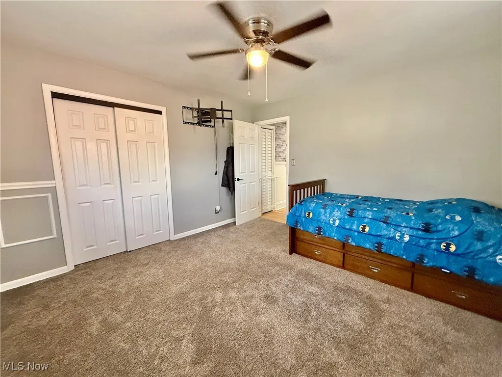 Unfurnished bedroom with a closet, carpet, and a ceiling fan