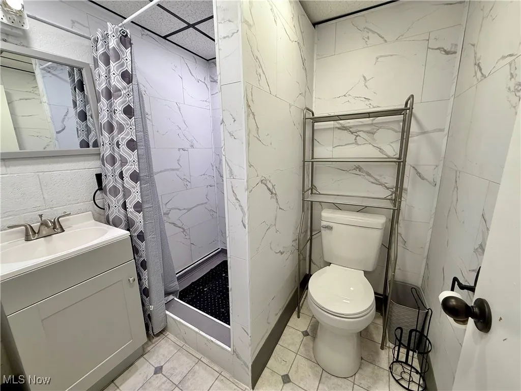 Bathroom featuring vanity, tile walls, a shower stall, and light tile patterned flooring