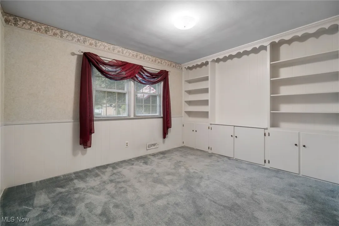 Empty room featuring carpet floors and a wainscoted wall
