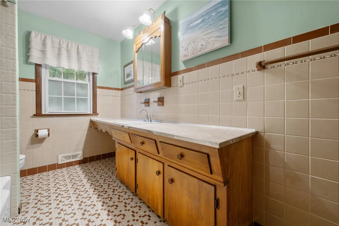 Bathroom with tile walls, vanity, and​​‌​​​​‌​​‌‌​‌‌​​​‌‌​‌​‌​‌​​​‌​​ wainscoting