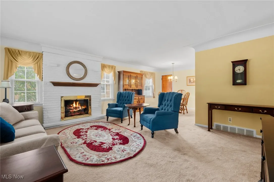 Living area with healthy amount of natural light, carpet, a chandelier, and a fireplace