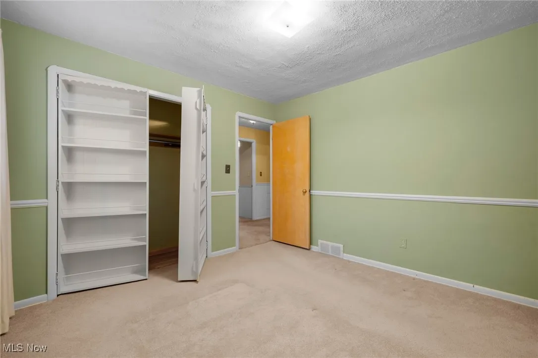 Unfurnished bedroom with carpet, a textured ceiling, and a closet