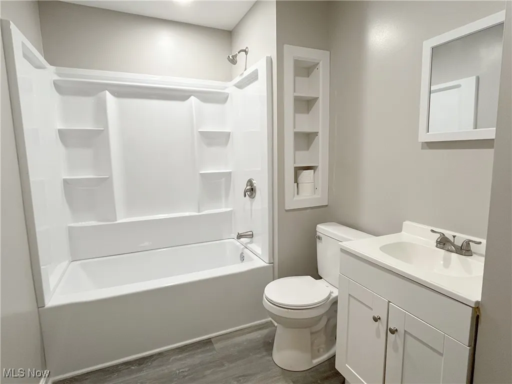 Full bath featuring vanity, dark wood-style floors, and  shower combination