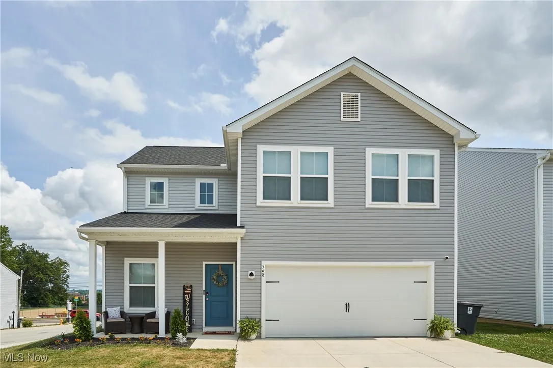 View of front of home with a porch, a garage, driveway, and a shingled roof