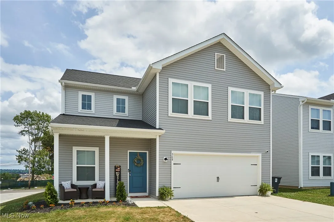 View of front of home with a porch, concrete driveway, a garage, and roof with shingles