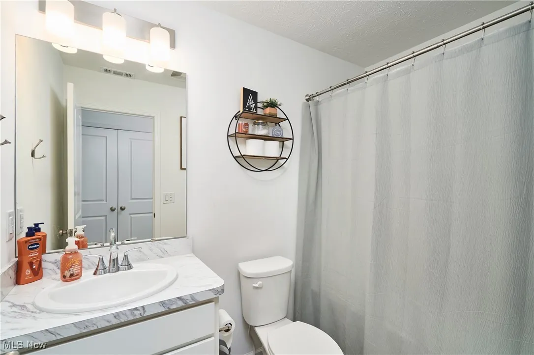 Full bathroom featuring vanity, a textured ceiling, and a shower with curtain