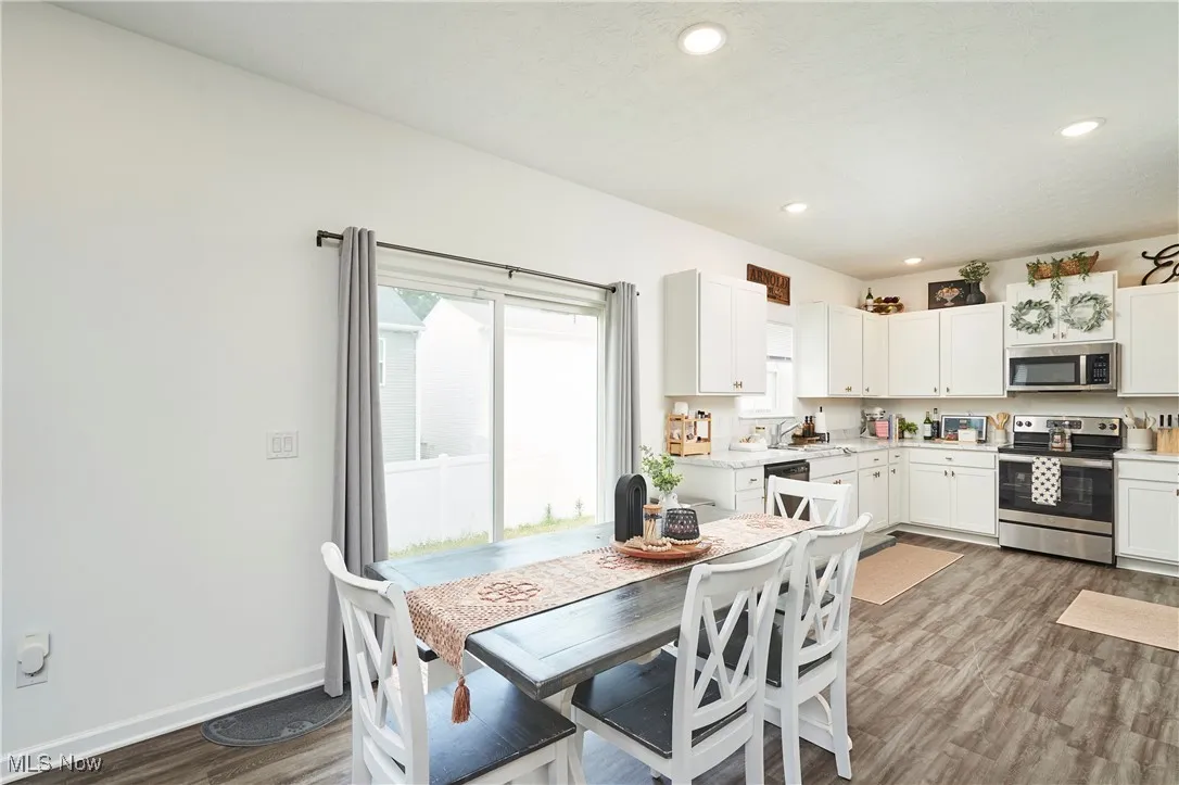 Kitchen featuring appliances with stainless steel finishes, LVP wood-type flooring, white cabinets, and recessed lighting