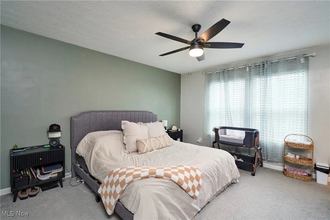 Carpeted bedroom featuring a textured ceiling and ceiling fan