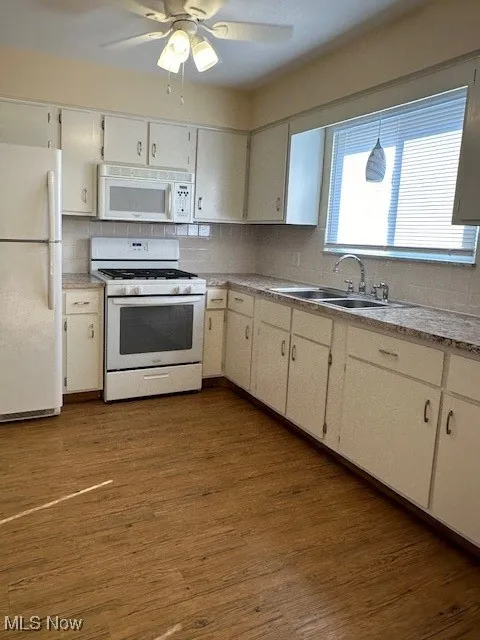 Kitchen featuring sink, dark wood-type flooring, fridge, and range