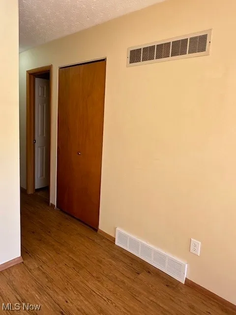 Spare room with wood-type flooring and a textured ceiling