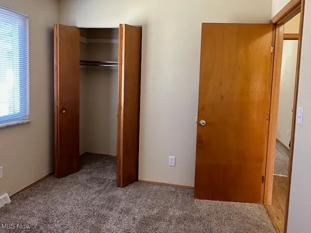 Unfurnished bedroom featuring a closet and light carpet