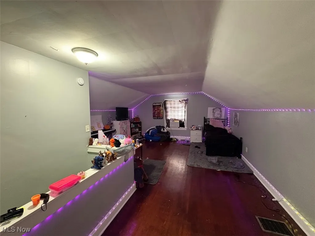 Bedroom with dark wood-style floors and lofted ceiling