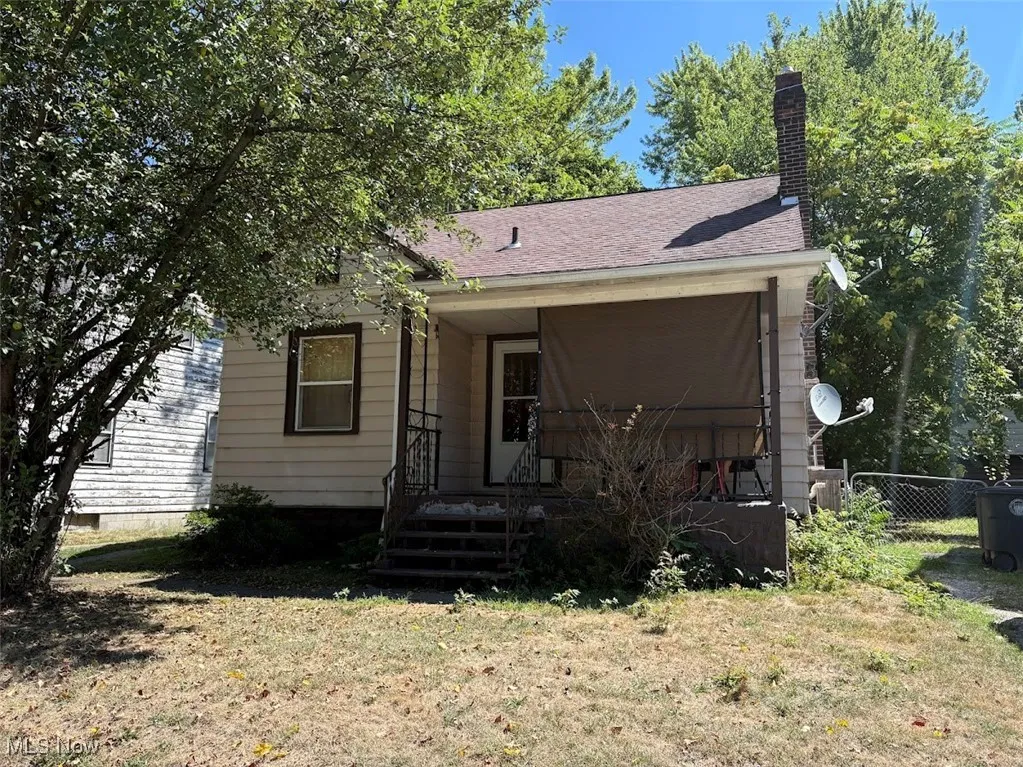 View of front of home with a chimney, a shingled roof, and covered porch