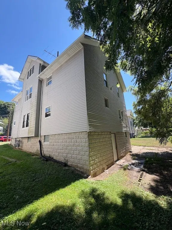 View of side of property with a lawn