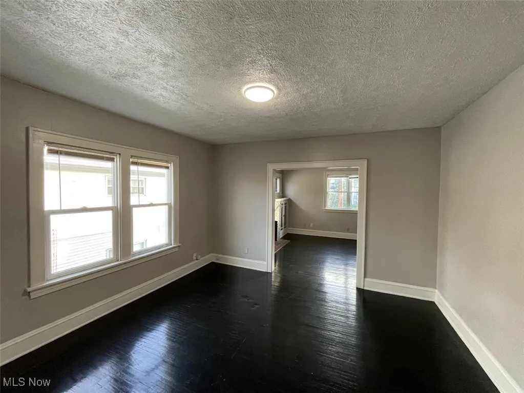 Spare room featuring dark wood-style flooring and a textured ceiling