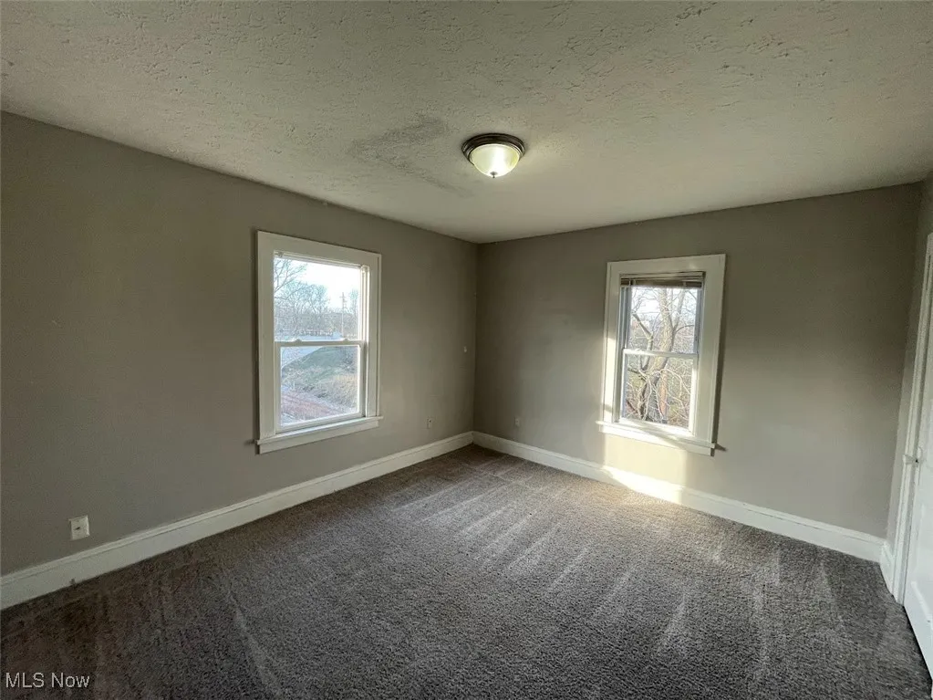 Unfurnished room with a textured ceiling and carpet flooring