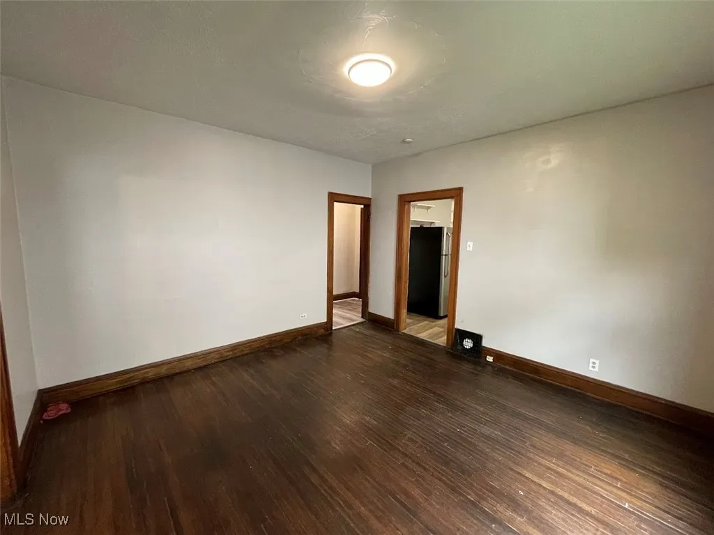 Spare room with dark wood-style flooring and baseboards