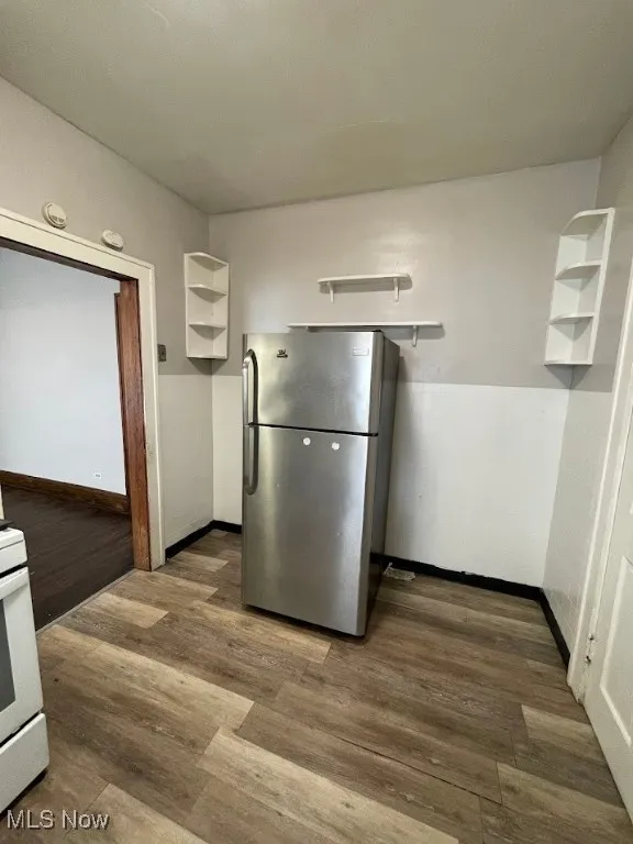 Kitchen featuring open shelves, freestanding refrigerator, dark wood finished floors, and white range with gas stovetop