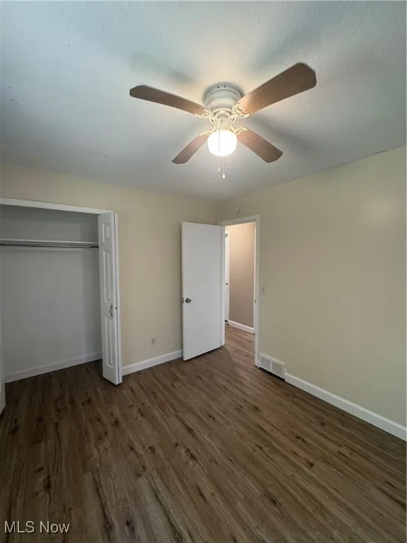 Unfurnished bedroom featuring dark wood-style flooring, a ceiling fan, a closet, and a textured ceiling