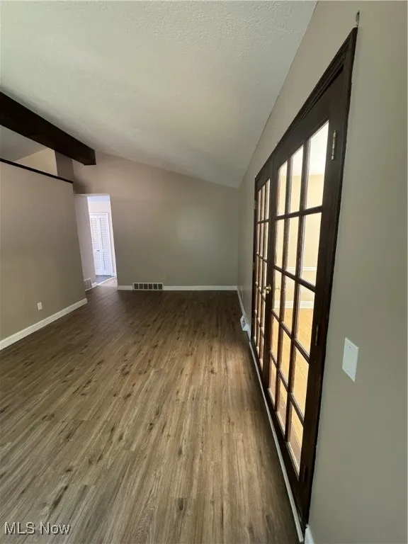 Unfurnished room with a textured ceiling, dark wood-style flooring, and french doors