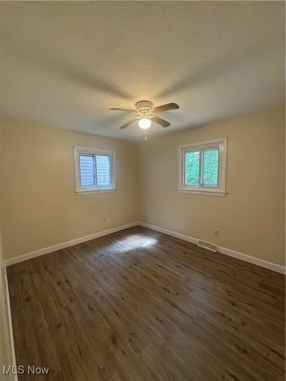 Empty room featuring dark wood-type flooring and a textured ceiling