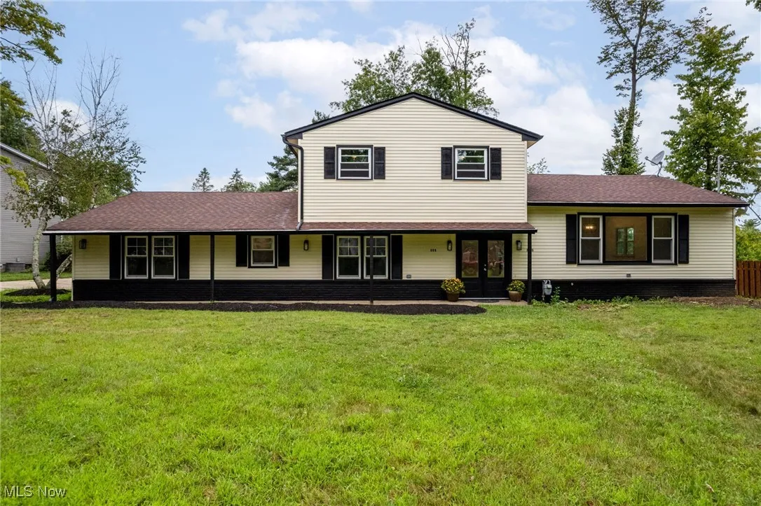 View of front facade with covered porch, a shingled roof, and a front yard