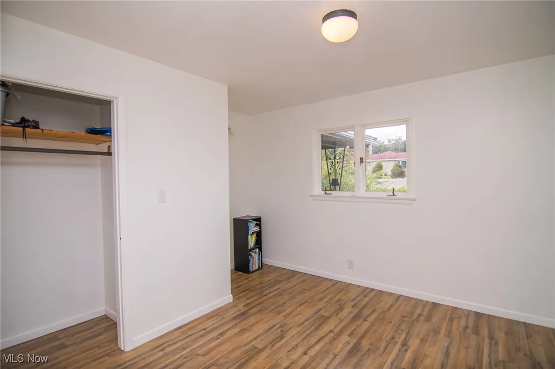 Unfurnished bedroom featuring dark wood-style flooring and a closet