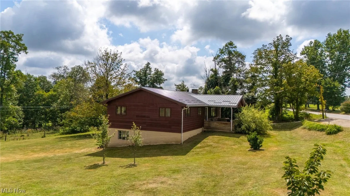 View of property exterior with a lawn, a metal roof, and covered porch