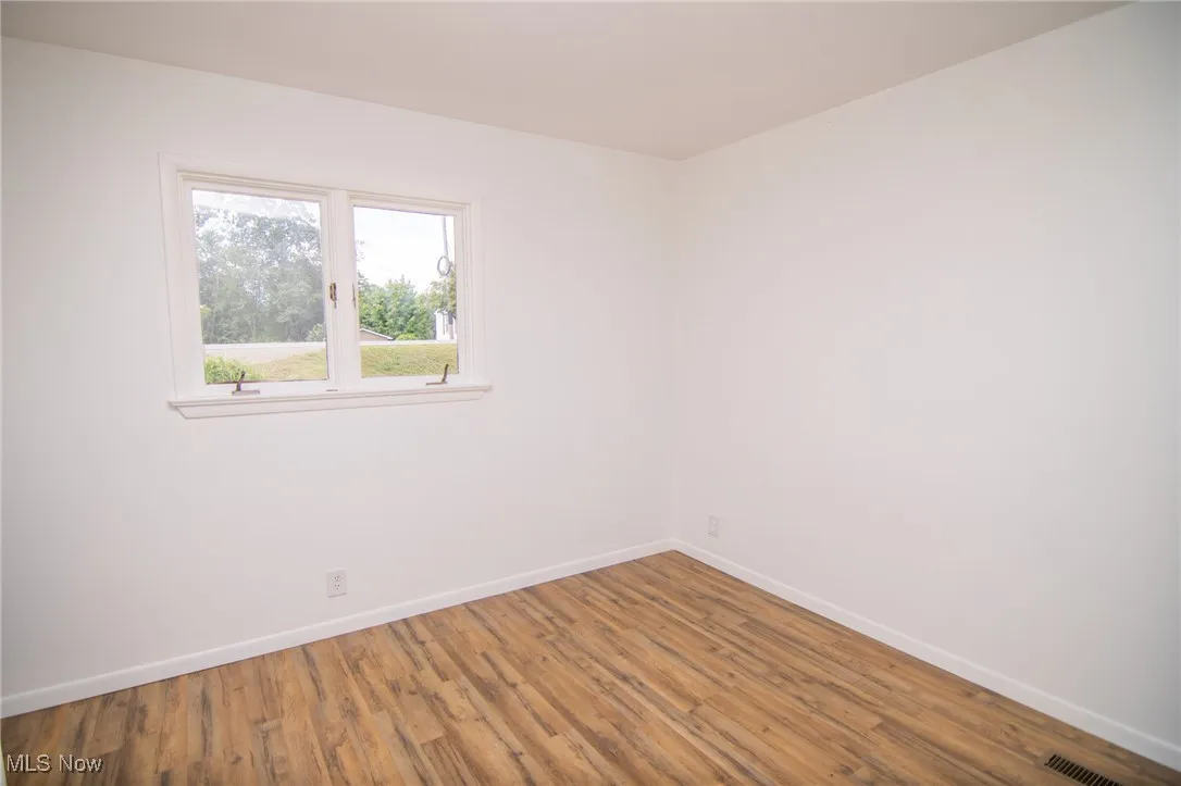 Unfurnished room featuring wood finished floors and baseboards