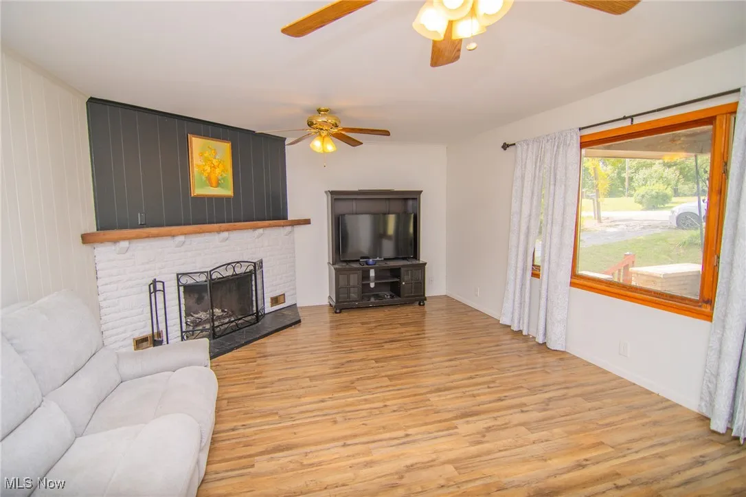 Living area featuring light wood-style flooring, a fireplace, and a ceiling fan