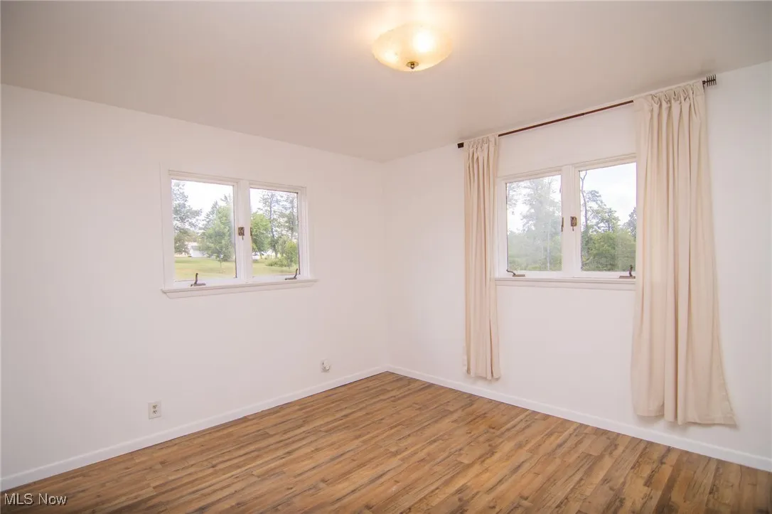 Unfurnished room featuring wood finished floors and plenty of natural light