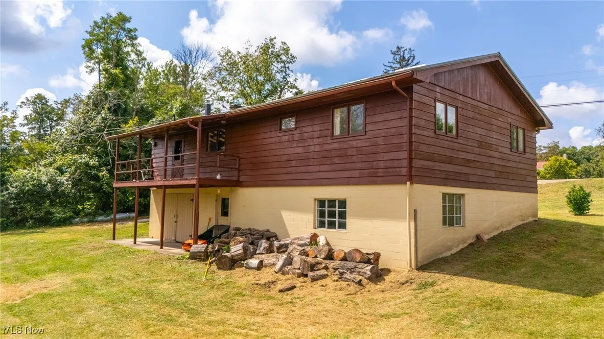 Back of property featuring a lawn, a wooden deck, and a patio area