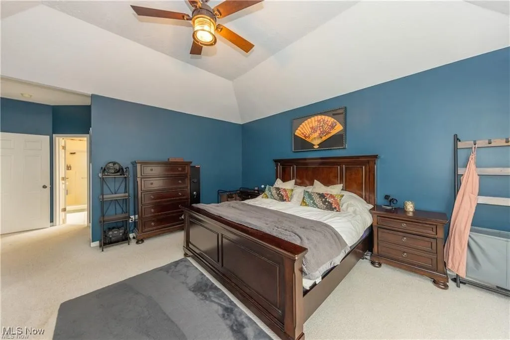 Bedroom with carpet floors, a ceiling fan, and vaulted ceiling