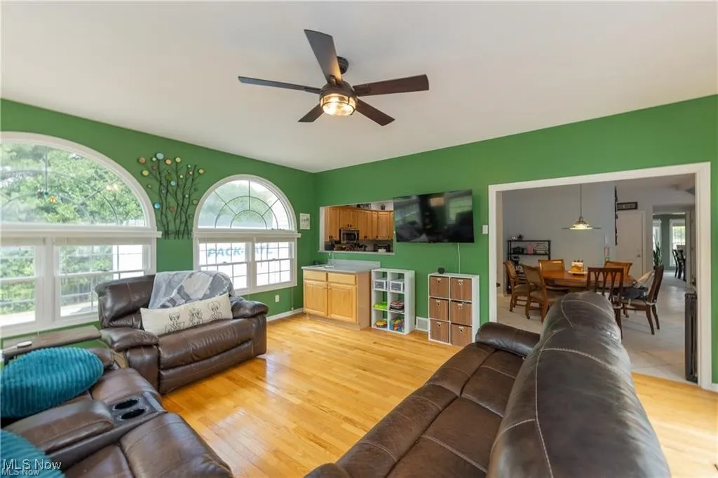 Living room featuring light wood-style floors, plenty of natural light, and a ceiling fan
