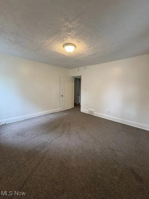 Empty room featuring carpet floors and a textured ceiling