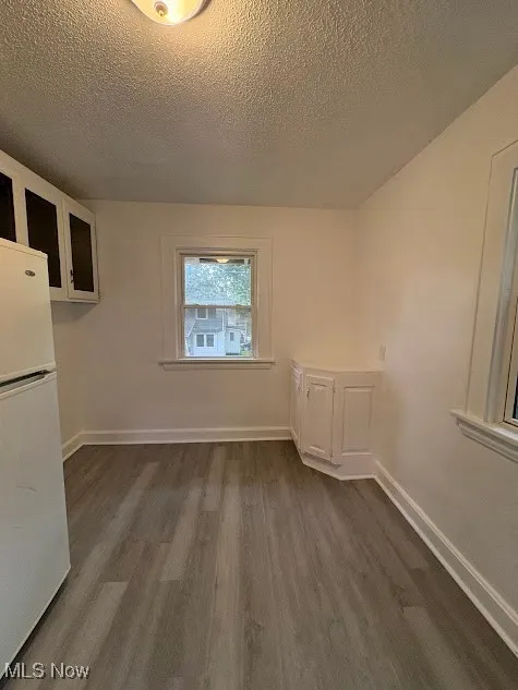 Unfurnished dining area featuring dark wood-type flooring and a textured ceiling
