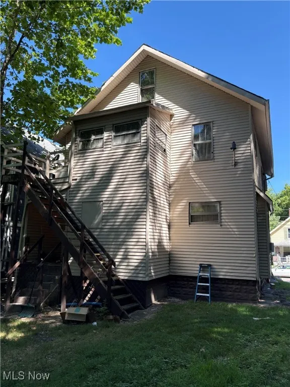 View of property exterior with stairway and a yard