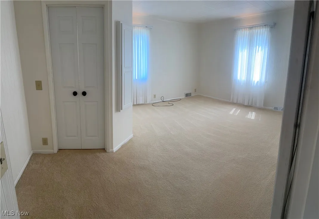 Unfurnished room featuring light colored carpet and baseboards