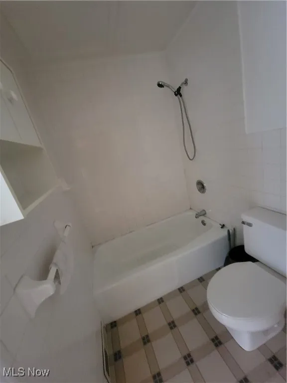 Full bath featuring bathing tub / shower combination and tile walls