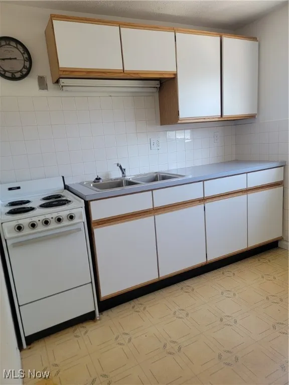 Kitchen with light flooring, white cabinets, range, light countertops, and brown cabinetry