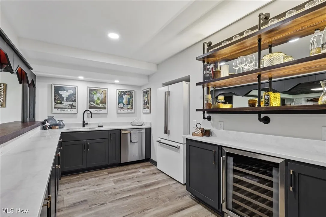 Indoor wet bar with wine cooler, open shelves, freestanding refrigerator, light wood-style floors, and dishwasher