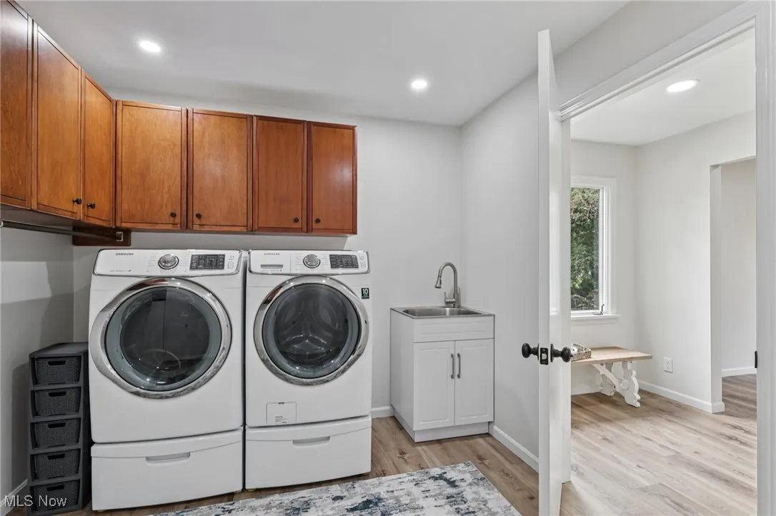 Washroom with light wood-style flooring, independent washer and dryer, recessed lighting, and cabinet space