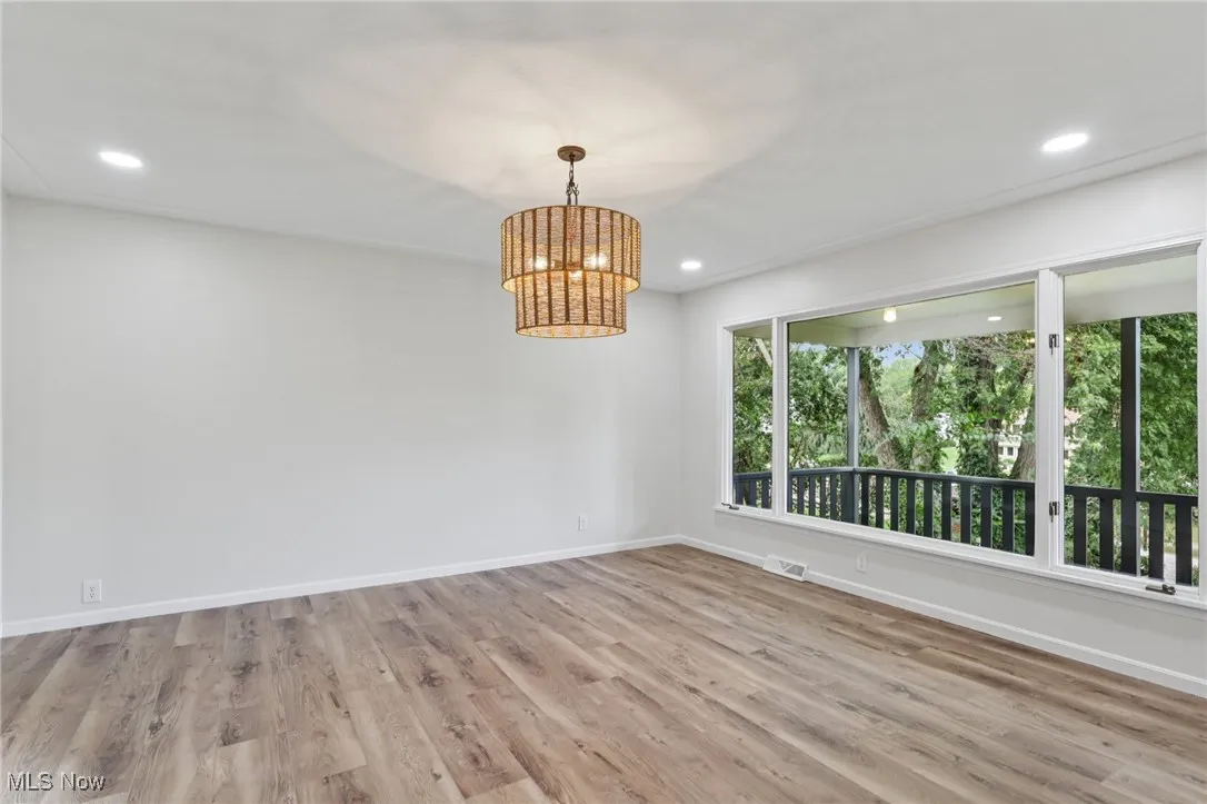 Empty room with light wood-style floors, a chandelier, and recessed lighting