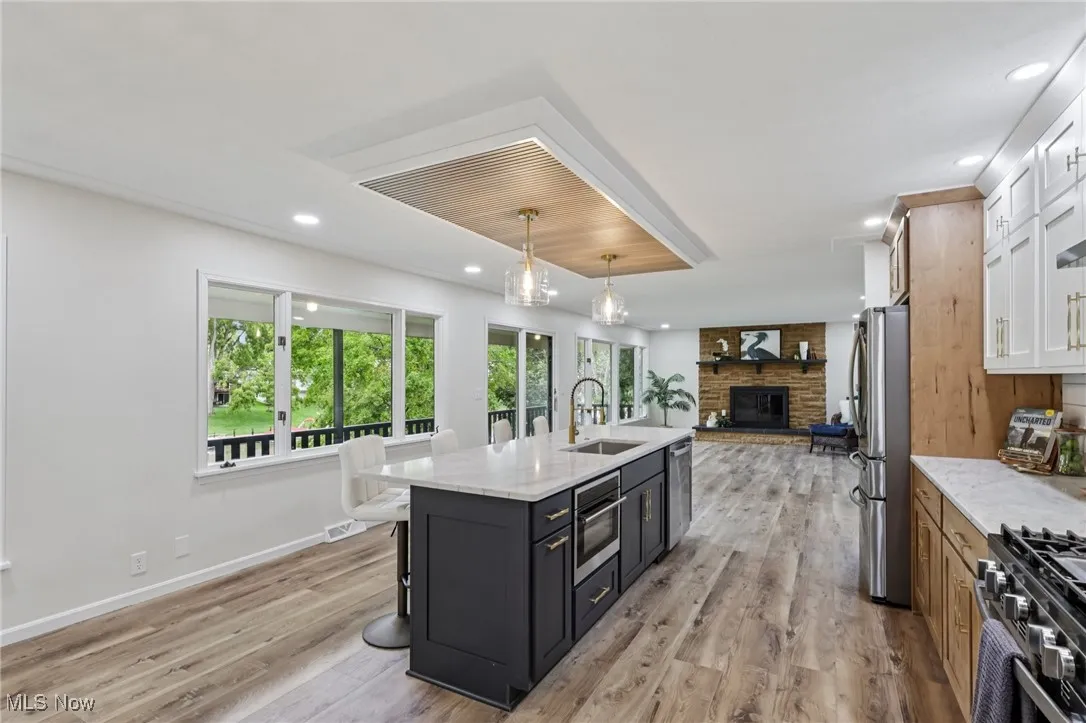 Kitchen with light stone countertops, dark cabinetry, light wood finished floors, and recessed lighting