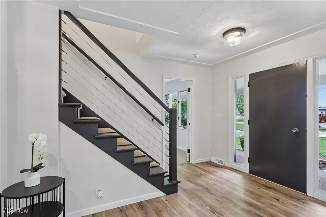 Foyer entrance featuring light wood-type flooring, stairs, and a textured ceiling