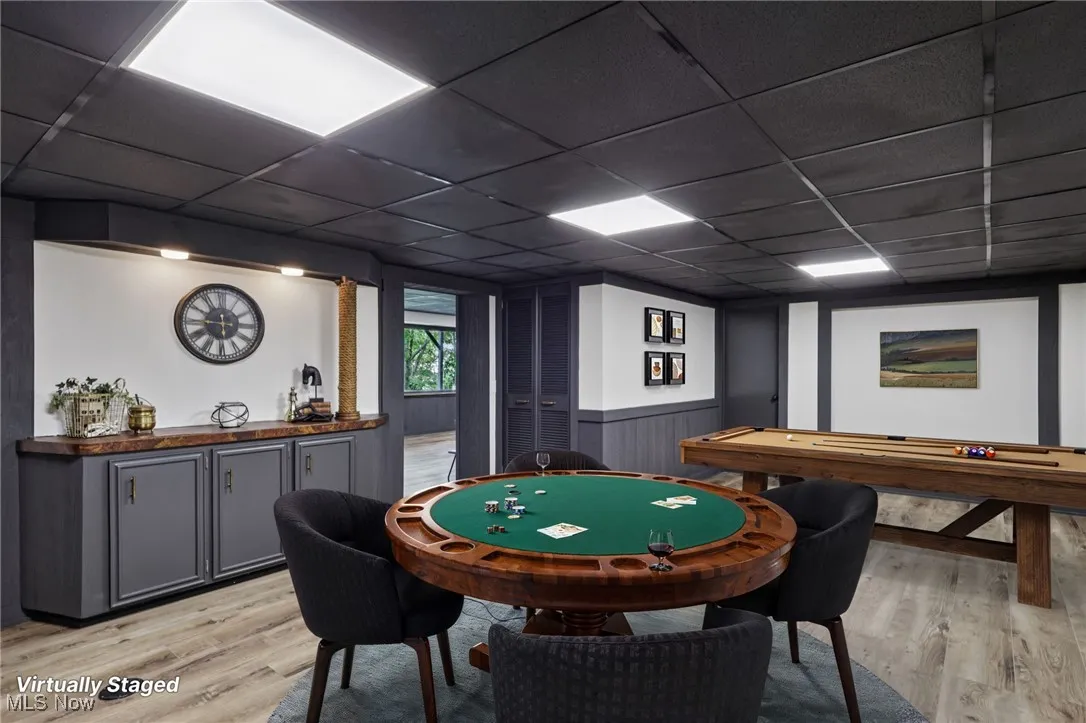 Game room featuring a drop ceiling, light wood-style flooring, and wainscoting