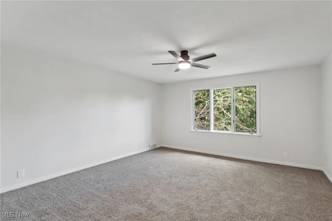 Empty room with carpet and a ceiling fan