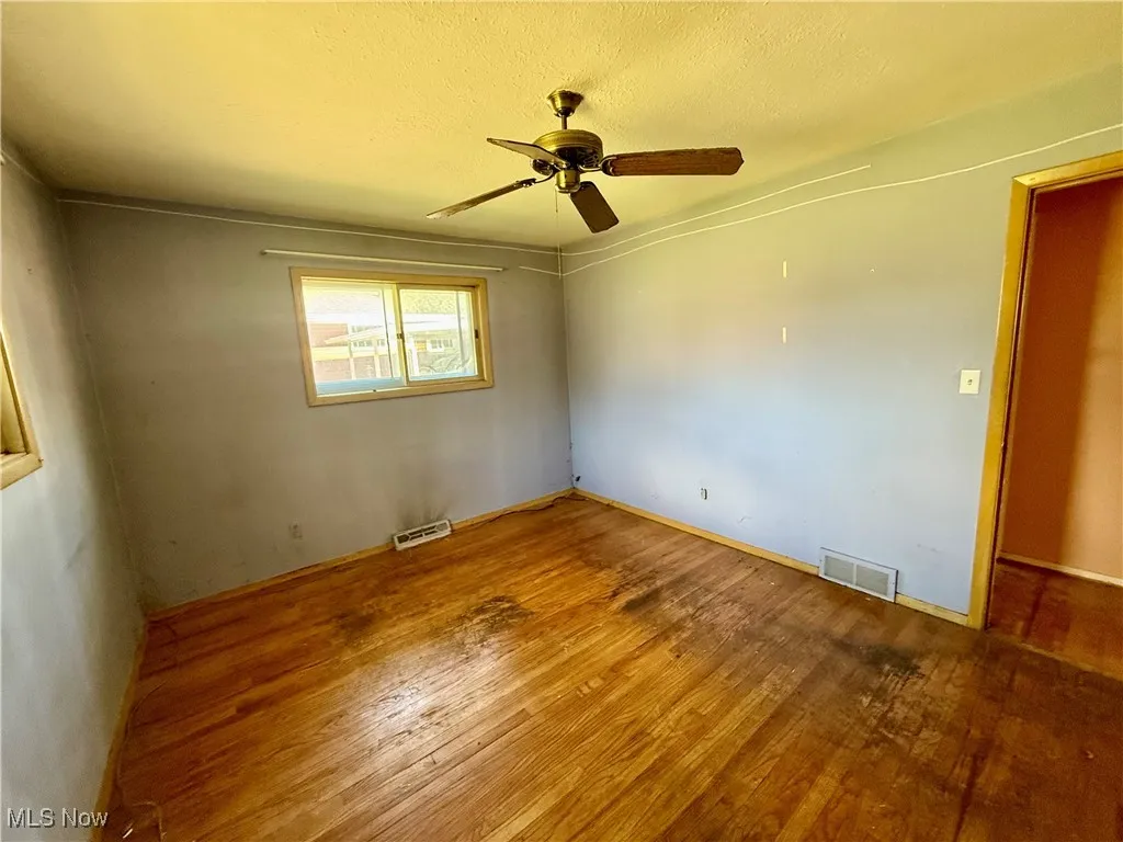 Unfurnished room with wood-type flooring, a textured ceiling, and a ceiling fan
